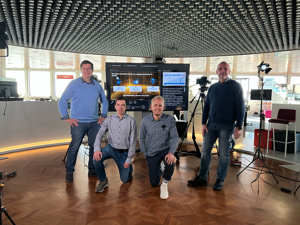Vier Teammitglieder von OT Analytics in einem modernen Workspace vor Monitor und Kameraequipment.