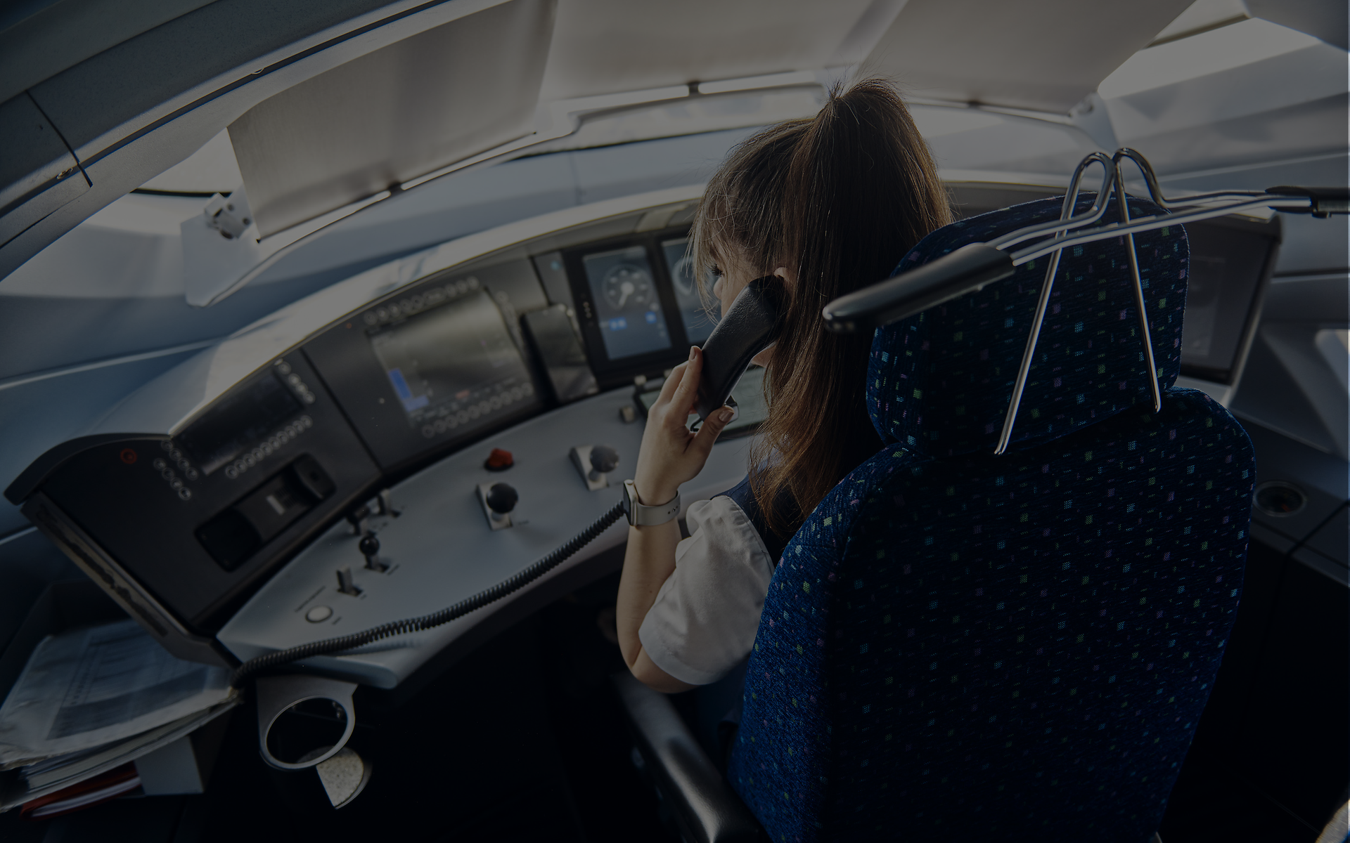 Lokführerin im Führerstand telefoniert als Beispiel für sprachgestützte Kommunikation und Übersetzung im Bahnverkehr.