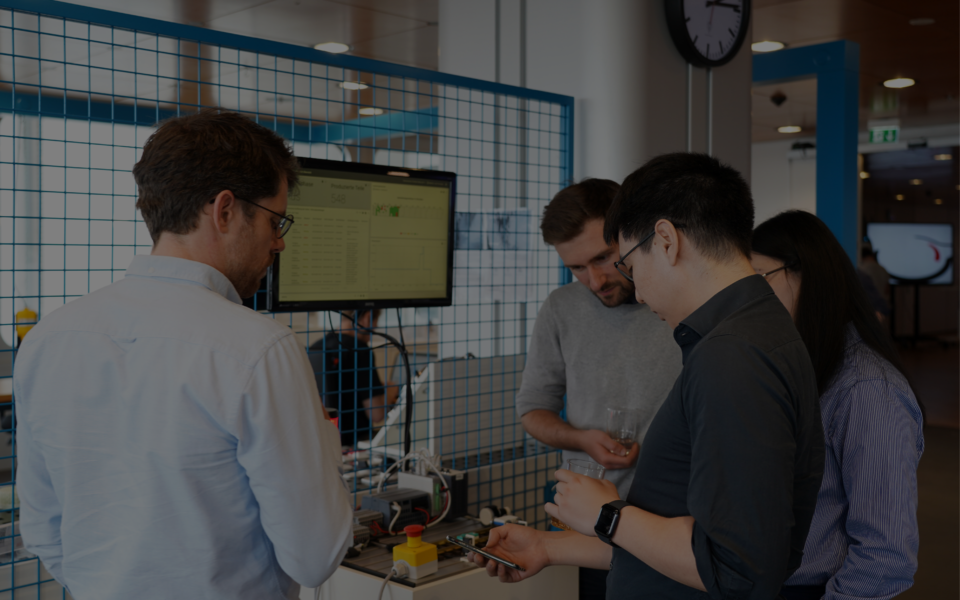 Personengruppe diskutiert vor einem großen Bildschirm im Innovationsbereich des Skydeck.